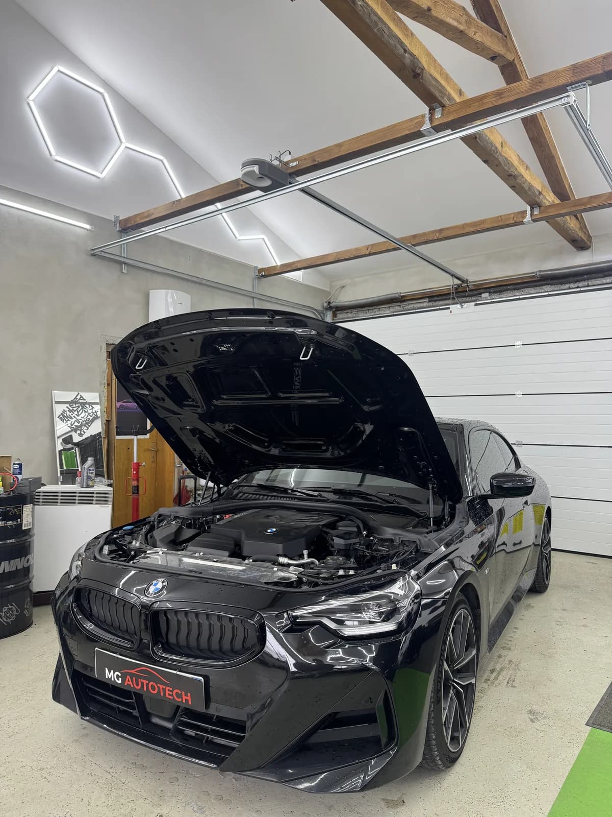 BMW mit geöffnetem Motorraum während der technischen Prüfung bei MG AutoTech